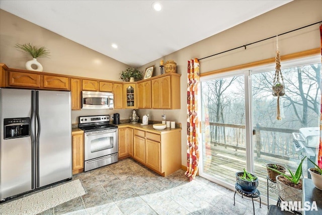 kitchen featuring glass insert cabinets, stainless steel appliances, light countertops, recessed lighting, and vaulted ceiling