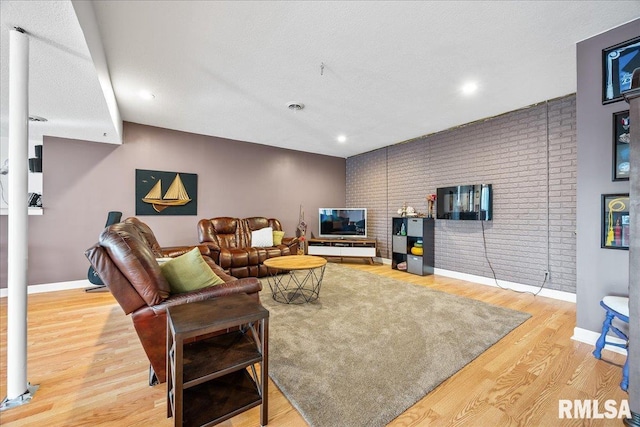 living area featuring recessed lighting, brick wall, wood finished floors, and baseboards