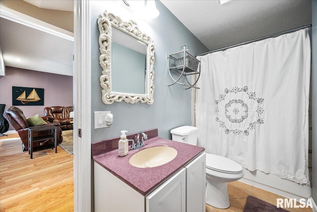 full bath with wood finished floors, shower / bath combination with curtain, toilet, vanity, and a textured ceiling