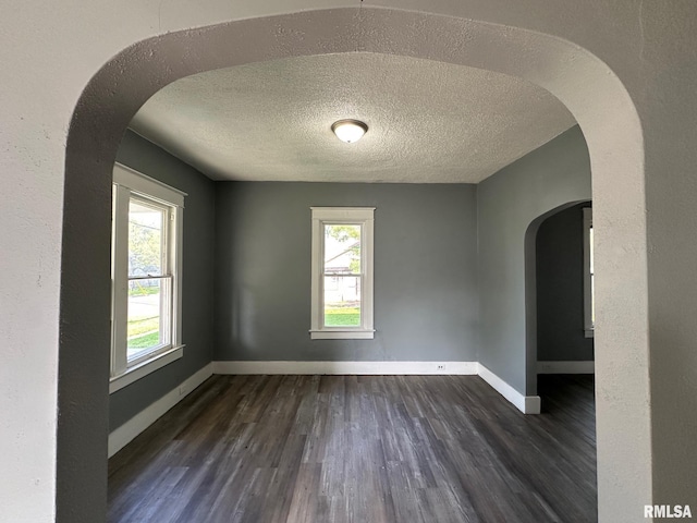 921 W Brons Ave, Peoria, IL 61604 - unfurnished room with dark wood-style floors, arched walkways, a textured ceiling, and baseboards