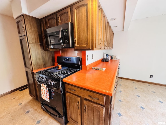 711 E Piper St, Macomb, IL 61455 - kitchen featuring stainless steel microwave, black gas stove, light tile patterned flooring, and baseboards