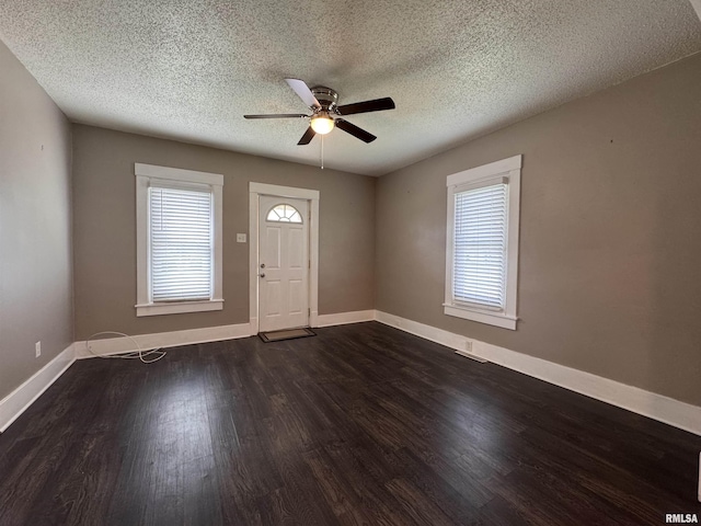 foyer with a ceiling fan, a textured ceiling, baseboards, and dark wood-type flooring
