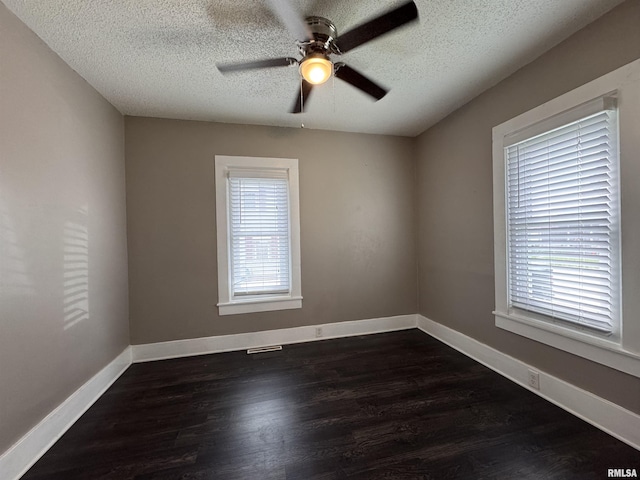 empty room featuring dark wood-type flooring, a textured ceiling, ceiling fan, and baseboards