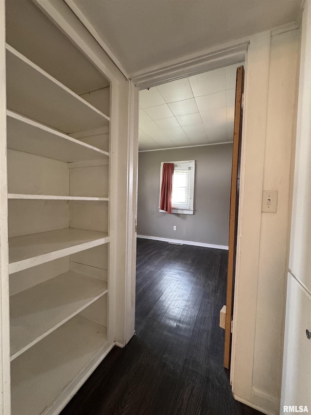 hall featuring baseboards and dark wood-style flooring
