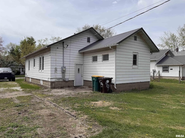 back of property with a yard, a standing seam roof, and metal roof