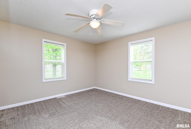 carpeted empty room with a wealth of natural light, baseboards, and a ceiling fan
