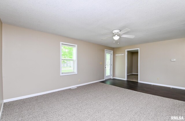 unfurnished room featuring a ceiling fan, baseboards, dark colored carpet, and a textured ceiling