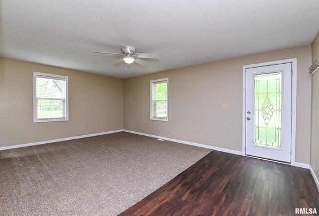 spare room with baseboards, dark wood finished floors, and ceiling fan