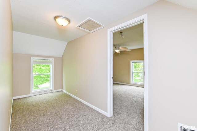 unfurnished room featuring lofted ceiling, attic access, carpet, baseboards, and visible vents