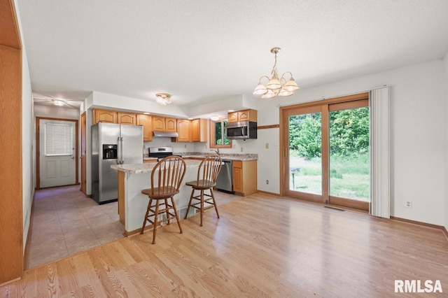 25633 N County Road 2500 E, Manito, IL 61546 - kitchen featuring stainless steel appliances, a chandelier, a center island, a kitchen breakfast bar, and light wood-style flooring