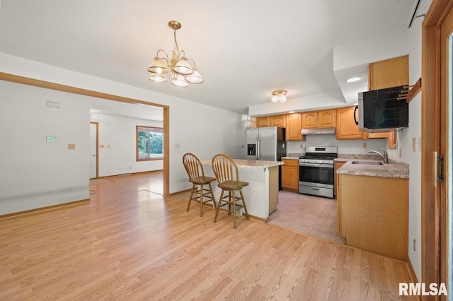 25633 N County Road 2500 E, Manito, IL 61546 - kitchen with stainless steel appliances, a sink, under cabinet range hood, light countertops, and a kitchen bar