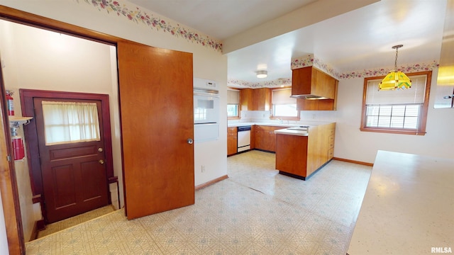 kitchen featuring brown cabinets, light countertops, a peninsula, light floors, and white appliances
