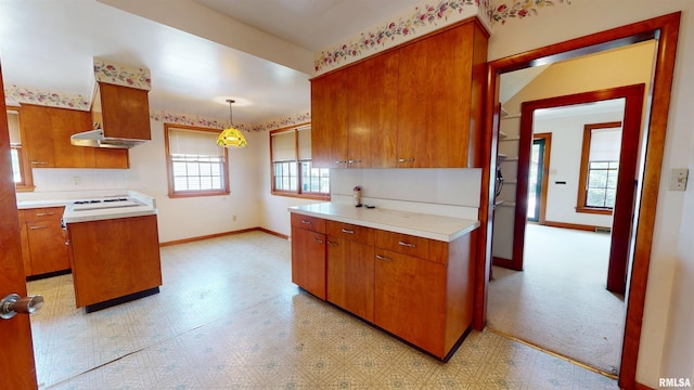 kitchen featuring brown cabinetry, white cooktop, light countertops, baseboards, and light floors