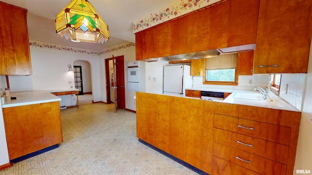 kitchen with a sink, light countertops, a peninsula, light floors, and white appliances