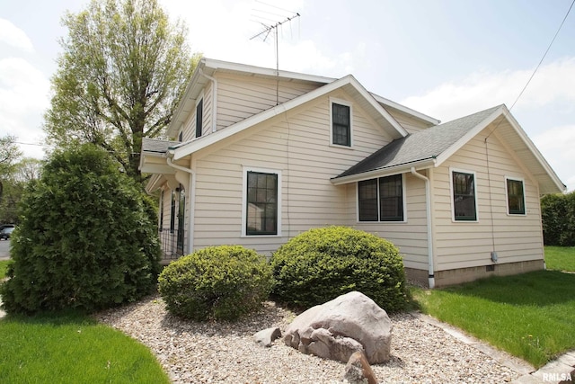 view of side of home featuring a shingled roof and a yard