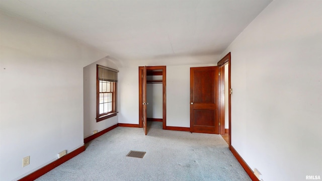 unfurnished bedroom featuring baseboards, visible vents, a closet, and light colored carpet