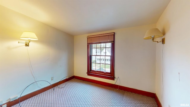 spare room with baseboards and carpet
