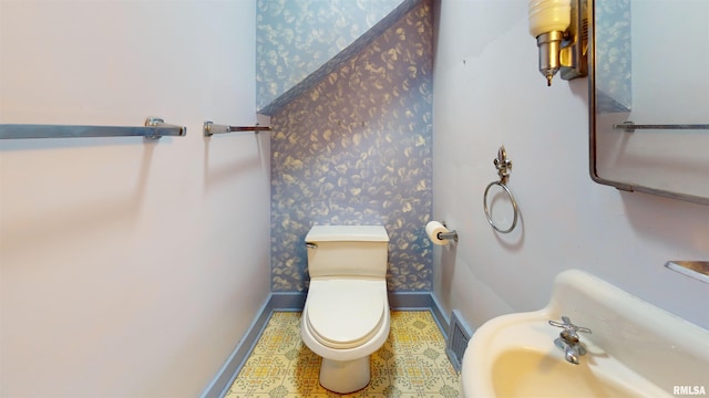 half bathroom featuring baseboards, toilet, wallpapered walls, and visible vents