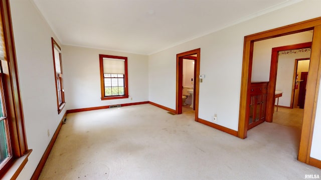 carpeted spare room featuring crown molding, baseboards, and visible vents
