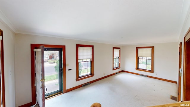carpeted foyer with crown molding, baseboards, and visible vents
