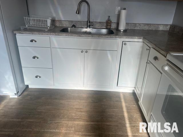 bar featuring a sink, dark wood finished floors, stove, and refrigerator