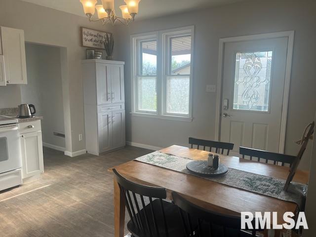 dining room featuring an inviting chandelier, baseboards, and light wood-type flooring