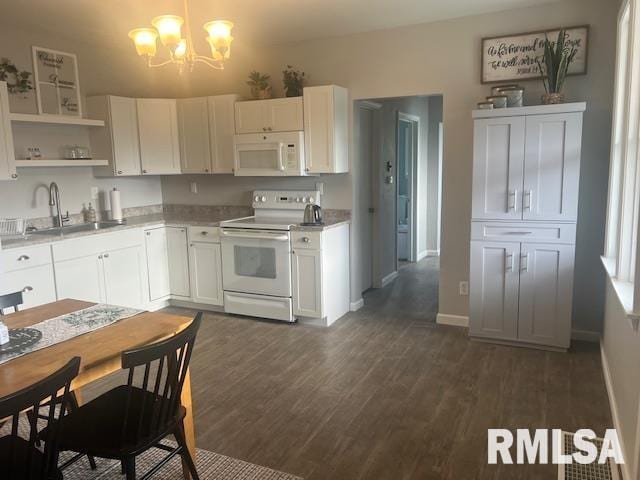 kitchen with white appliances, dark wood-style floors, white cabinetry, a sink, and a notable chandelier
