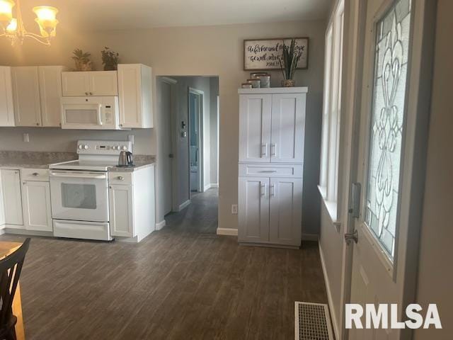 kitchen with visible vents, white appliances, dark wood-type flooring, white cabinetry, and a notable chandelier