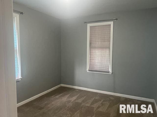 empty room featuring baseboards and dark colored carpet