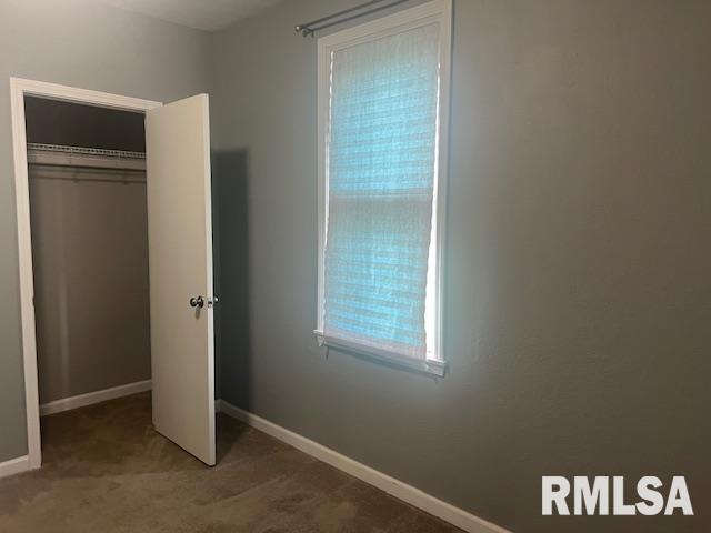 unfurnished bedroom featuring baseboards, carpet, and a closet