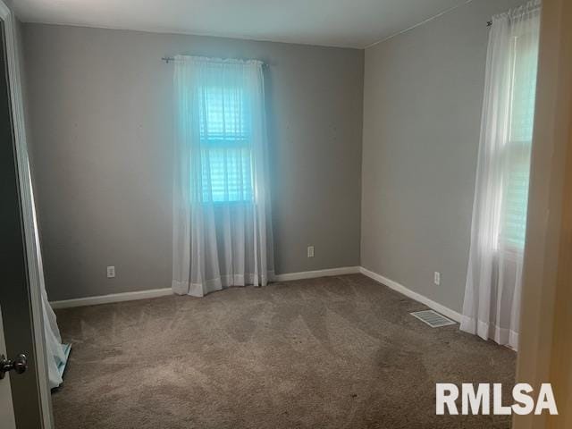 empty room featuring a healthy amount of sunlight, baseboards, carpet flooring, and visible vents