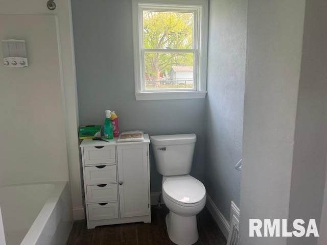 bathroom with toilet, wood finished floors, and a bathtub