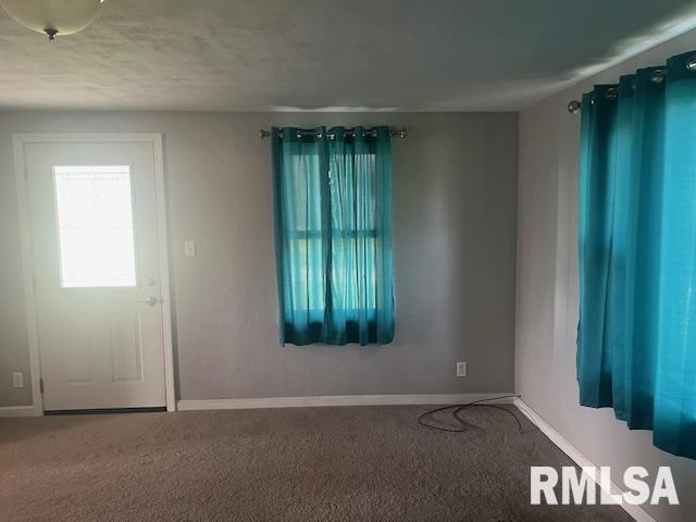 foyer entrance featuring baseboards and carpet flooring