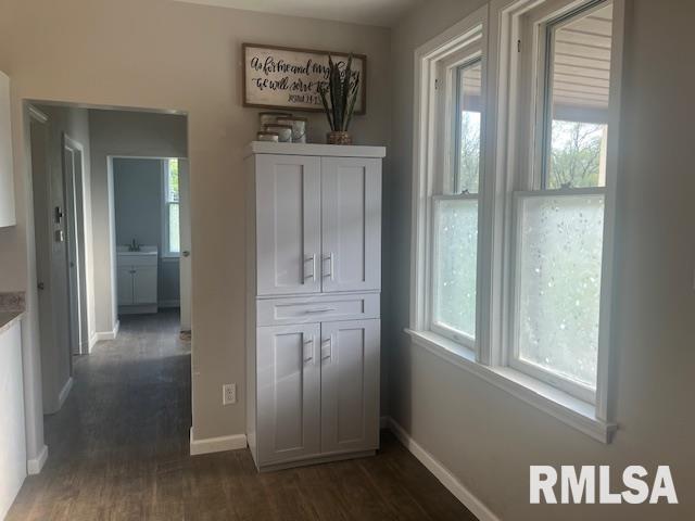 corridor with baseboards and dark wood-style floors