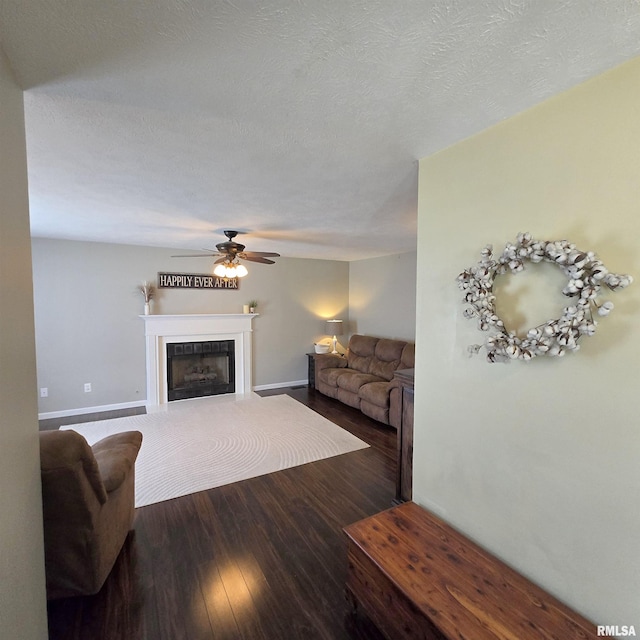 living room featuring baseboards, ceiling fan, wood finished floors, and a fireplace