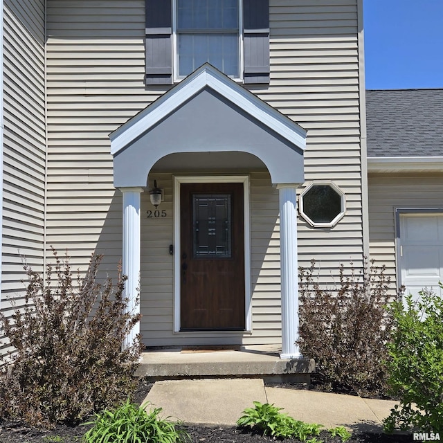 view of exterior entry featuring roof with shingles