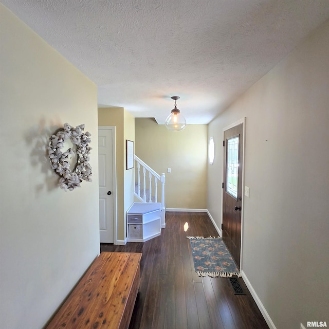 entrance foyer featuring baseboards, a textured ceiling, dark wood-style flooring, and stairs