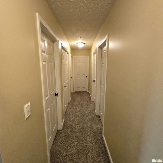 hall with baseboards, carpet flooring, and a textured ceiling