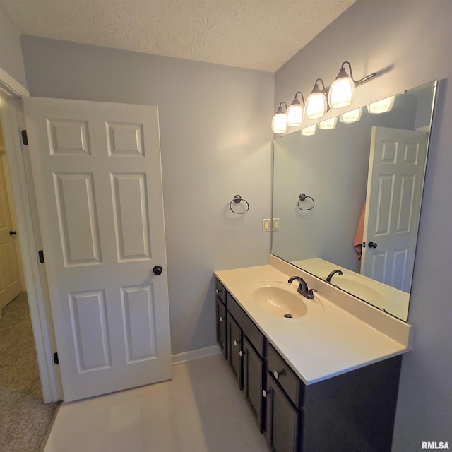 bathroom with vanity, baseboards, and a textured ceiling