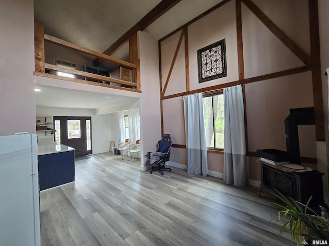 living area with light wood-style floors, high vaulted ceiling, baseboards, and visible vents