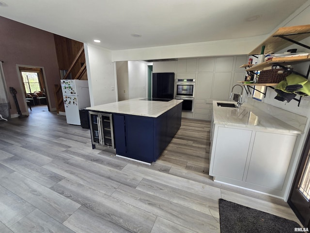 kitchen featuring stainless steel double oven, open shelves, a sink, freestanding refrigerator, and beverage cooler