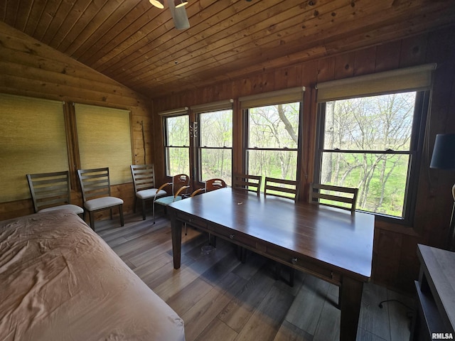 dining room with wood finished floors, wooden walls, wood ceiling, a ceiling fan, and vaulted ceiling