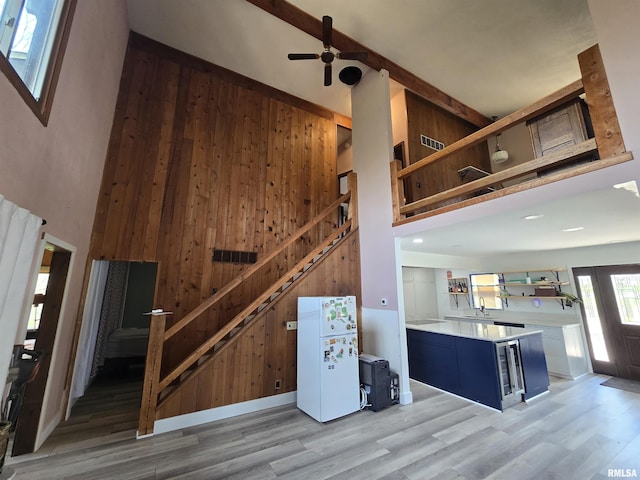 staircase with wood finished floors, wine cooler, a high ceiling, and wooden walls