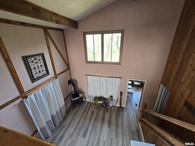 stairway featuring baseboards, a wood stove, wood finished floors, and lofted ceiling