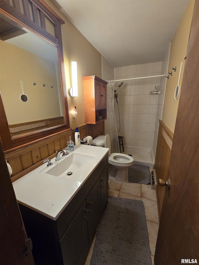 bathroom with vanity, toilet, tile patterned floors, a wainscoted wall, and a stall shower