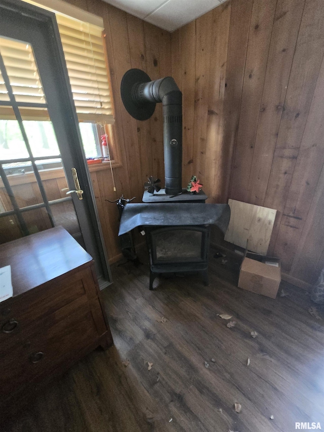 interior space featuring wooden walls, dark wood-style flooring, and a wood stove