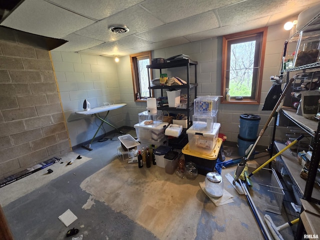 below grade area with concrete block wall, plenty of natural light, and a drop ceiling
