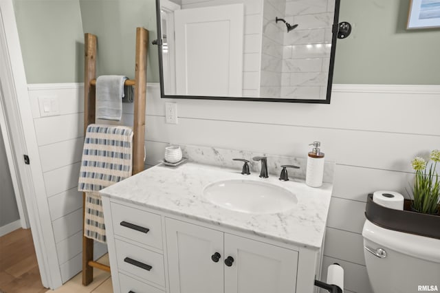 bathroom with vanity, wainscoting, toilet, and wood finished floors
