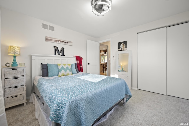 bedroom featuring baseboards, visible vents, light carpet, and a closet