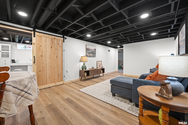 living room featuring a barn door, baseboards, and wood finished floors